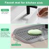 A silicone faucet mat with a 5-degree slope design placed in a kitchen sink, showing water drainage.