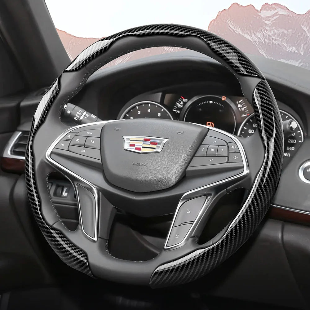 A close-up view of a black steering wheel with a glossy carbon fiber wrap and an airbag cover.