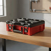A red and black modular stackable tool organizer case resting on a wooden surface.
