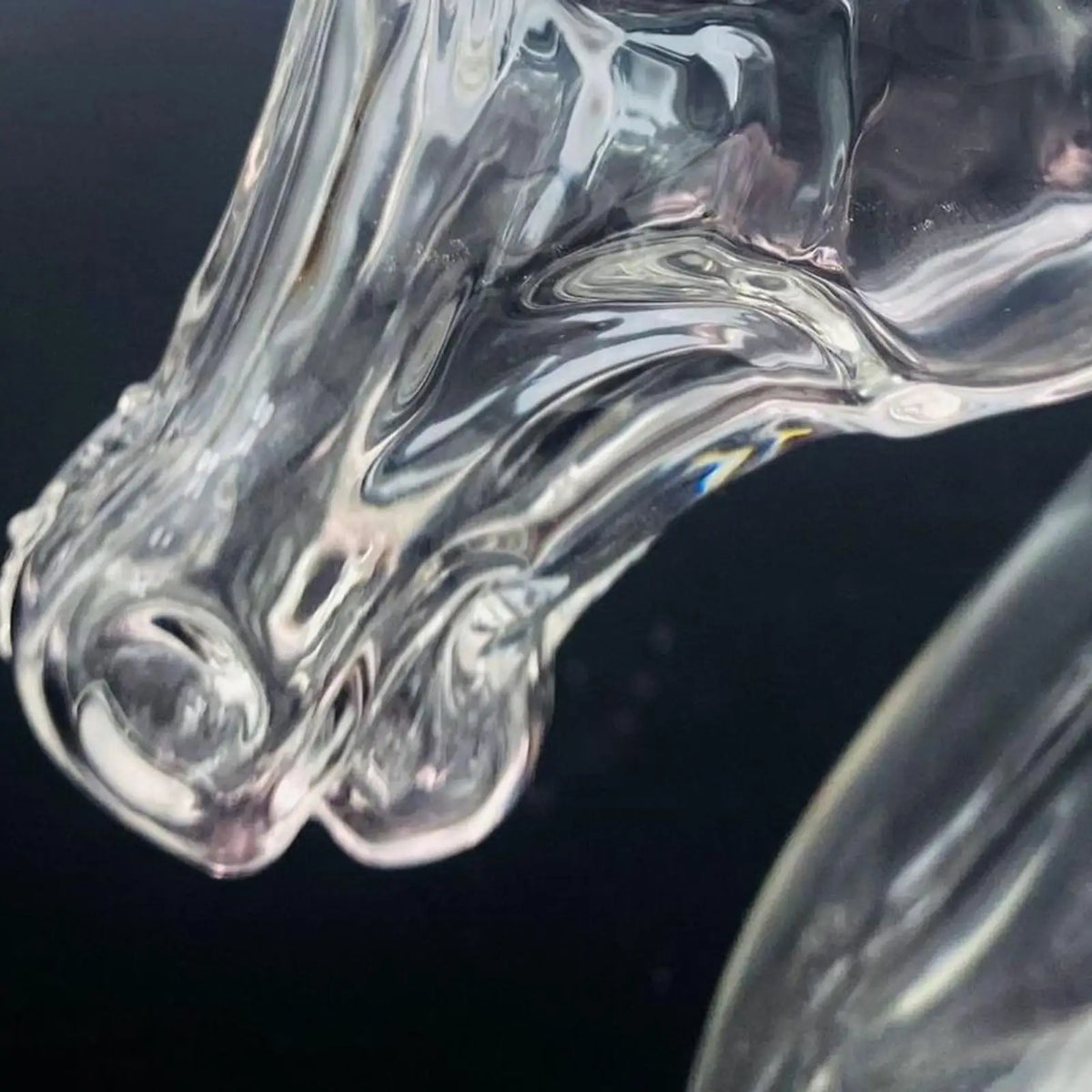A clear glass decanter shaped like a horse head, showing intricate details and curves.