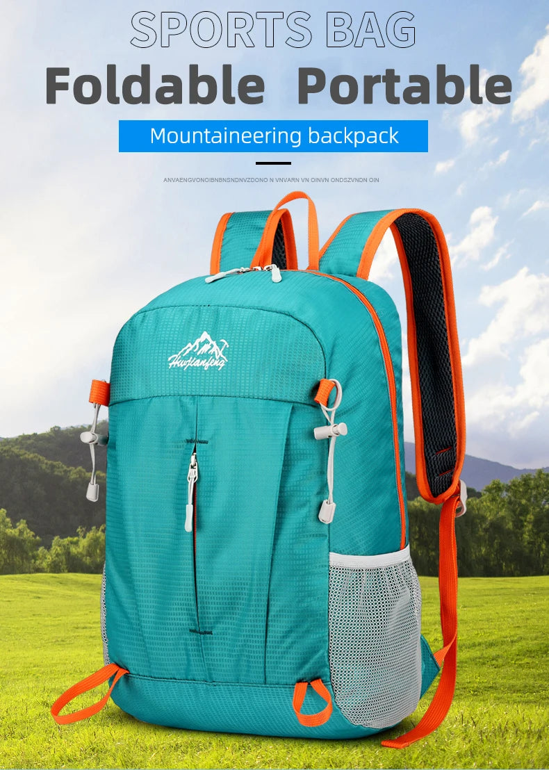 A teal foldable portable mountaineering backpack with orange accents shown outdoors on a grassy field.