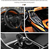Close-up view of a glossy carbon fiber steering wheel cover and interior details of a sports car.