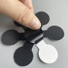 A hand is applying a black anti-slip shower sticker to a white surface.