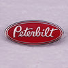 A red oval enamel pin featuring the white Peterbilt logo on a silver-toned metal background.