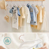 A child's hand is holding a white velvet hanger with a curved hook.