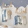 A display of wooden hangers and fabric clothing on a wall with a soft gray background.