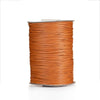 A spool of orange waxed cotton cord used for jewelry making.