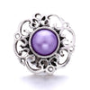 Silver metal snap button with a purple iridescent gemstone center and ornate floral design