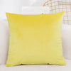A bright yellow velvet decorative cushion cover resting on a white textured surface.