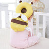 A toddler is wearing a yellow bee head protector backpack with brown stripes and white accents.