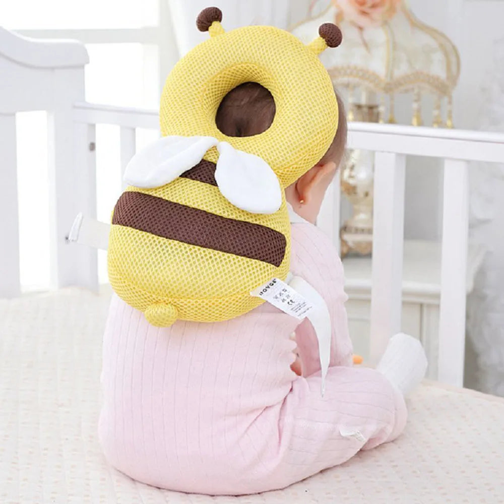 A toddler is wearing a yellow bee head protector backpack with brown stripes and white accents.