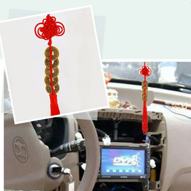 Chinese Feng Shui wealth coins with red handmade knot displayed in a car interior.
