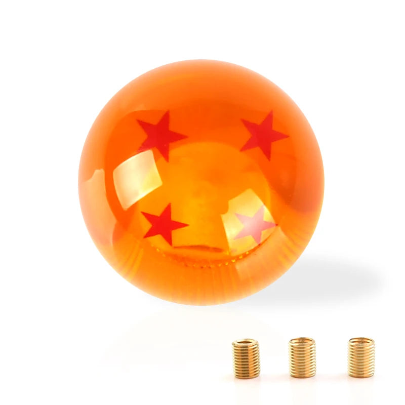 A glossy orange shift knob with a star design and three metallic cylindrical parts.