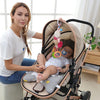 A woman holds a baby in a soft plush stroller mobile with hanging toys and bell.