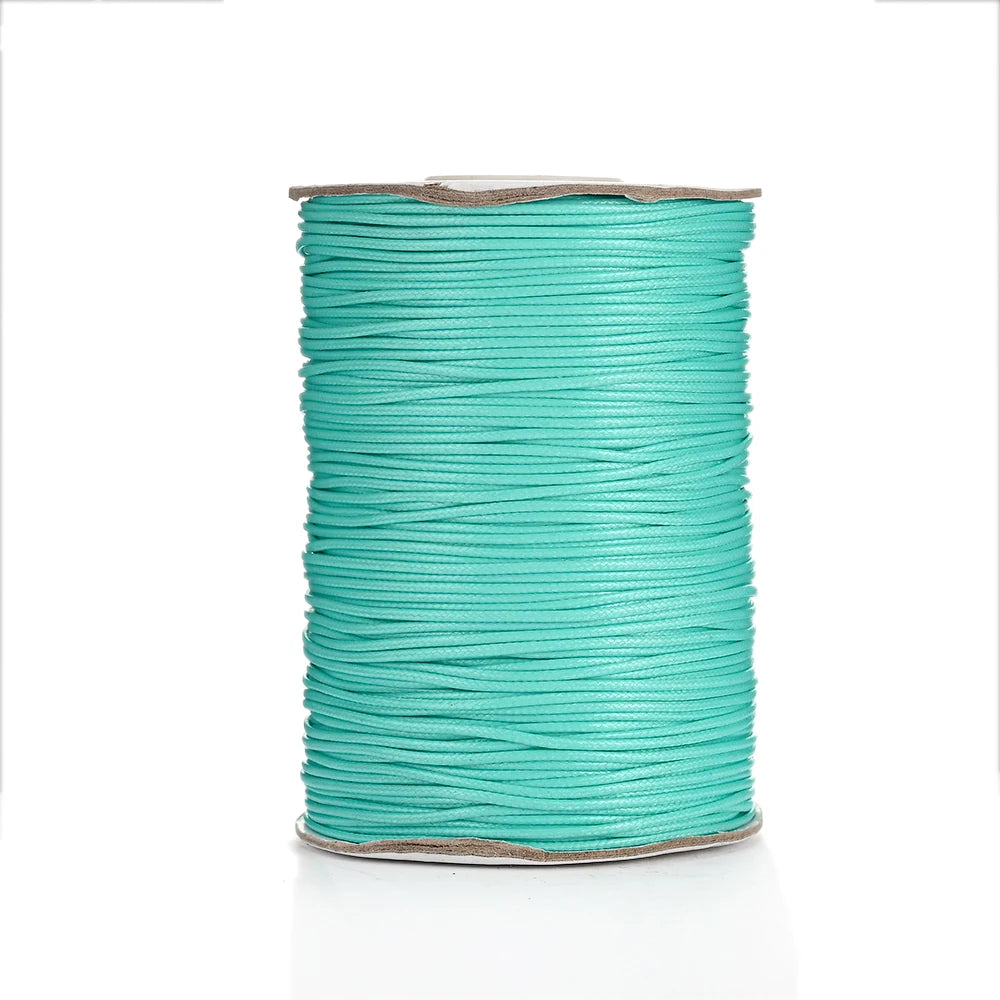 A spool of teal waxed cotton cord used for jewelry making.
