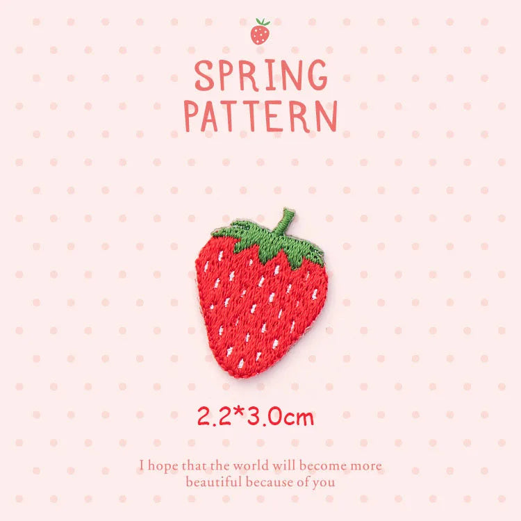 A red strawberry 3D embroidery patch with green leaves on a light pink background.