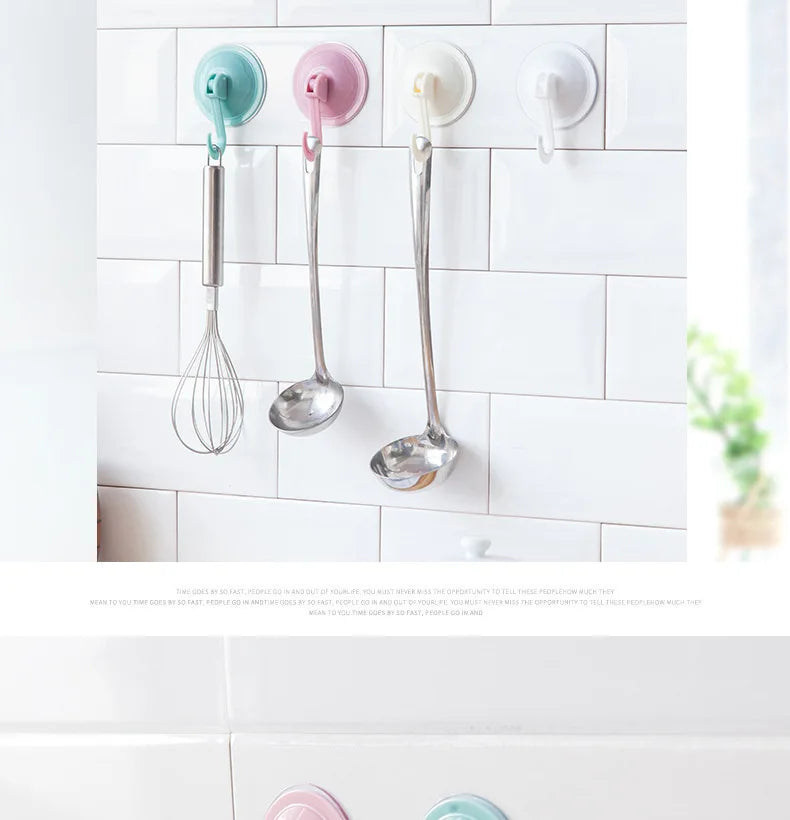 Three silicone kitchen utensils hanging on a white tiled backsplash with suction cup hooks