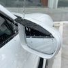 A close-up of a car's side mirror showing water dripping off the rain guard visor.