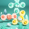 A light green suction cup spinner bath toy featuring a smiling sea creature and various shapes for toddlers.