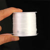A hand holds a spool of white elastic crystal beading cord for jewelry making.