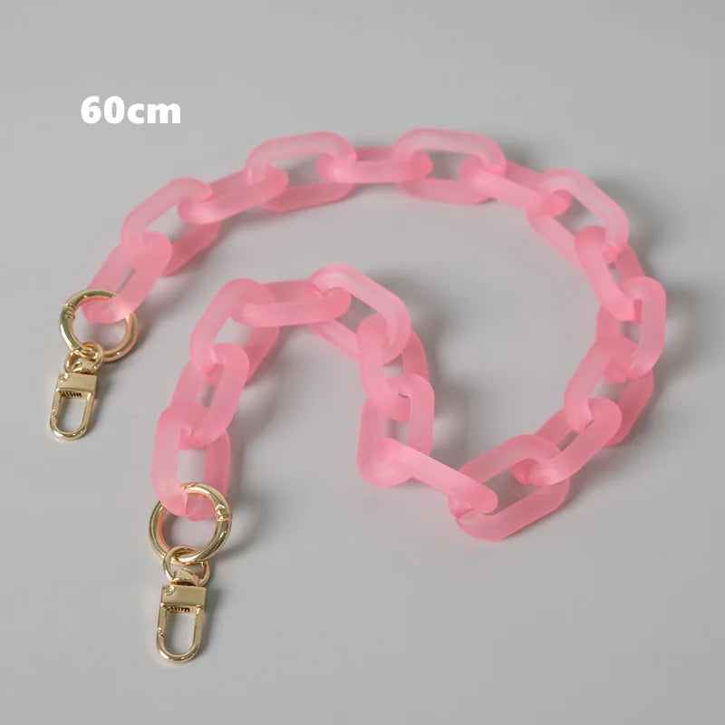 Rosa abnehmbare Kettengurt-Riemen für eine Tasche, ausgebreitet auf einer grauen Oberfläche.