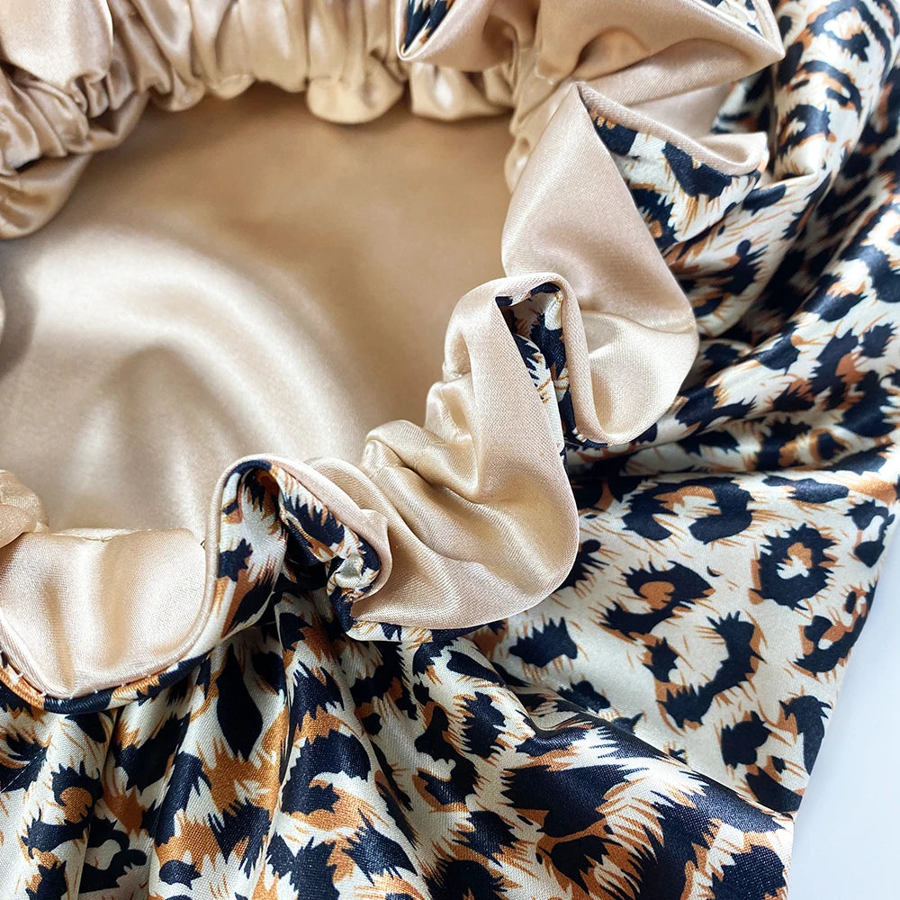 A close-up of a double-layer satin hair bonnet featuring a leopard print fabric with a beige lining.