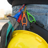 A close-up of a durable glove clip with an ergonomic grip attached to denim jeans and a yellow hard hat.