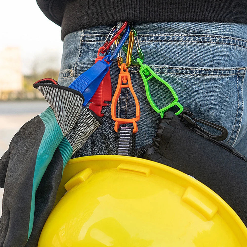A close-up of a durable glove clip with an ergonomic grip attached to denim jeans and a yellow hard hat.
