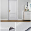 A white door and furniture featuring grey wood grain self-adhesive wallpaper.