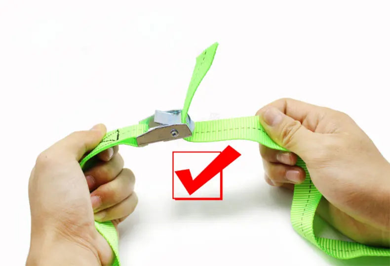 A hand is shown fastening a bright green heavy-duty tie-down strap with a metal buckle.