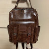 A brown PU leather fashion backpack hanging on a hook.