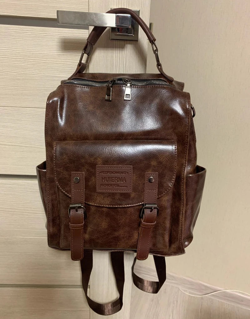 A brown PU leather fashion backpack hanging on a hook.