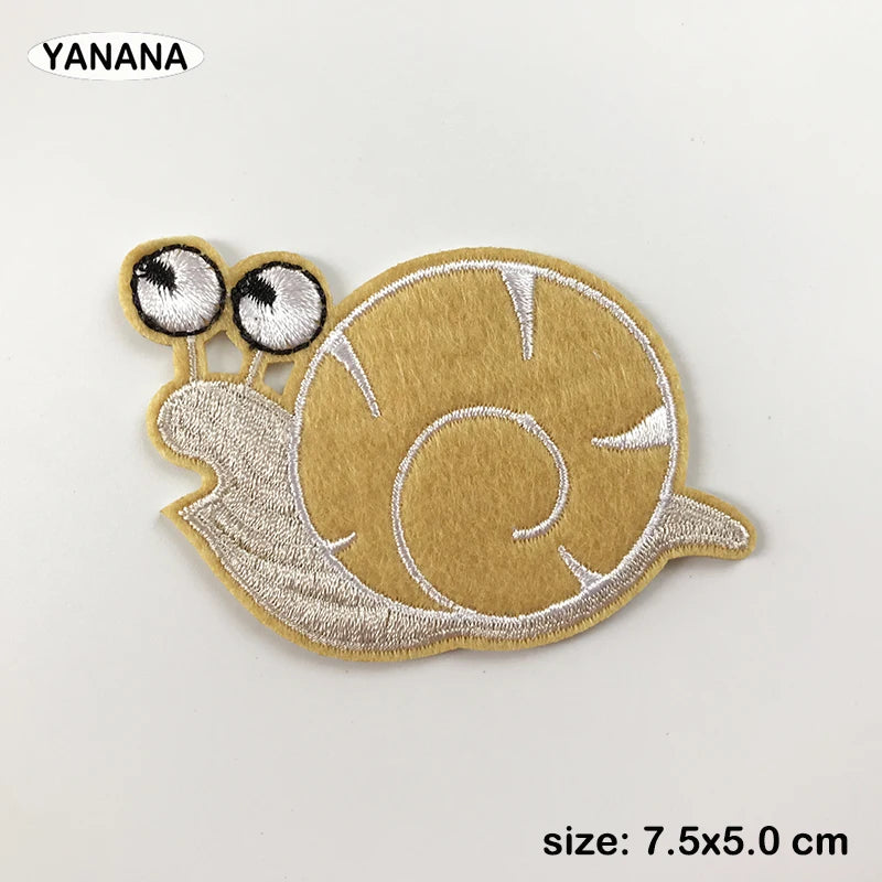 A round, tan embroidered patch of a sea turtle with large eyes and a spiral pattern.