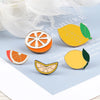 A collection of enamel fruit brooches featuring orange, lemon, and citrus designs on a light blue background.