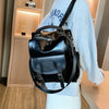 A black PU leather fashion backpack worn by a person, displayed in a light-colored room.