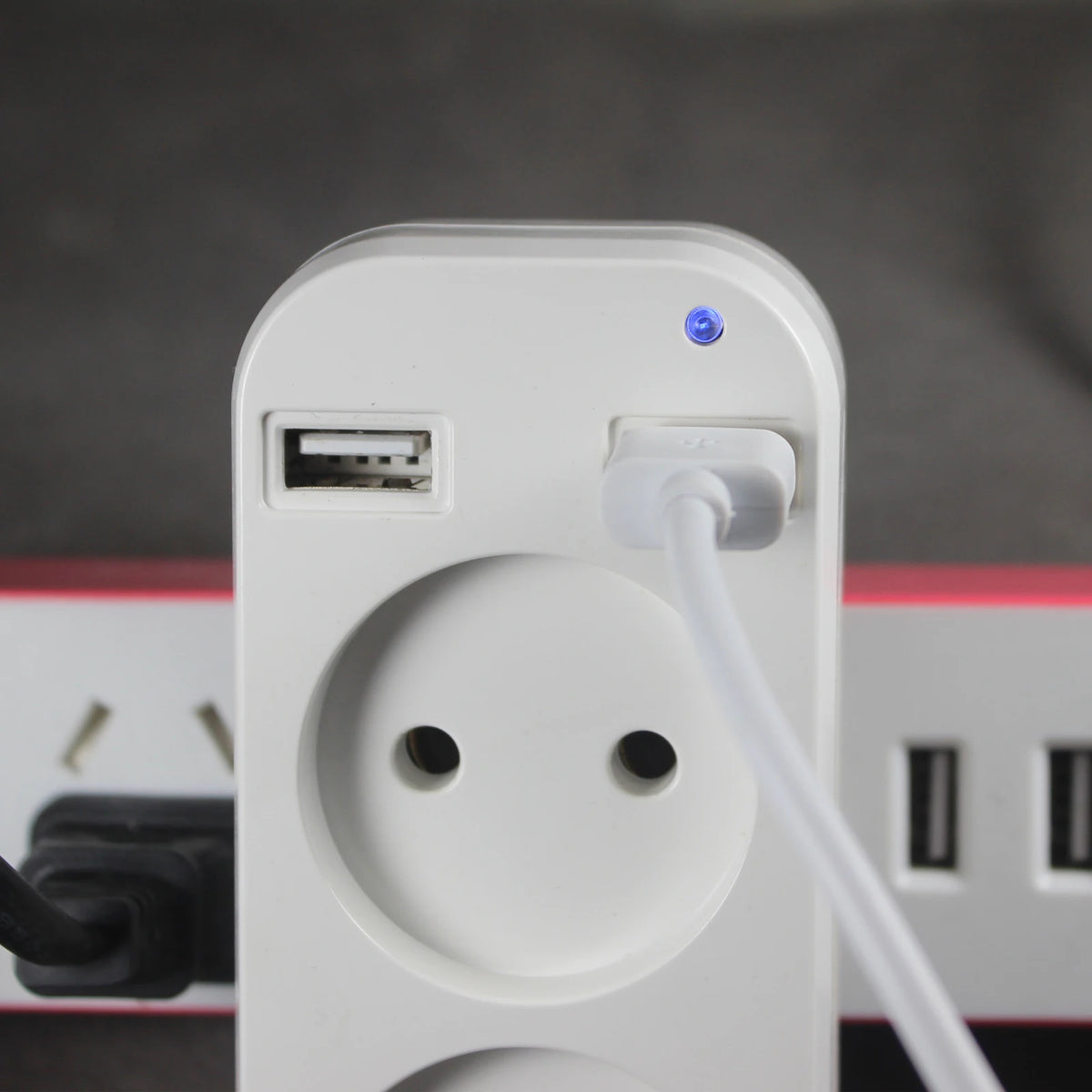 A white compact EU power strip with a USB port and a power cord plugged in.