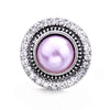 Round silver metal snap button with a purple pearl center surrounded by clear rhinestones