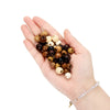 A hand holds a collection of natural wooden spacer beads in various shades of brown and cream.