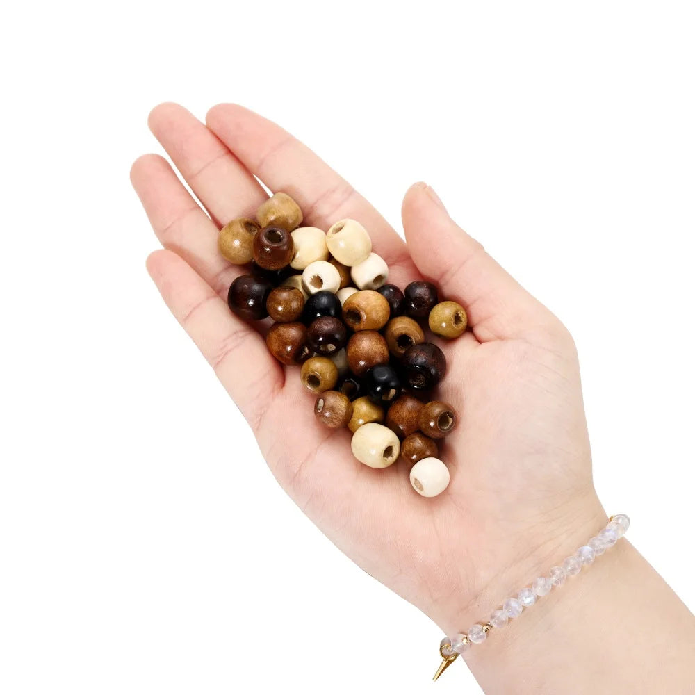 A hand holds a collection of natural wooden spacer beads in various shades of brown and cream.