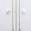 A white child safety cabinet lock mechanism with a long metal bar and mounting plates.