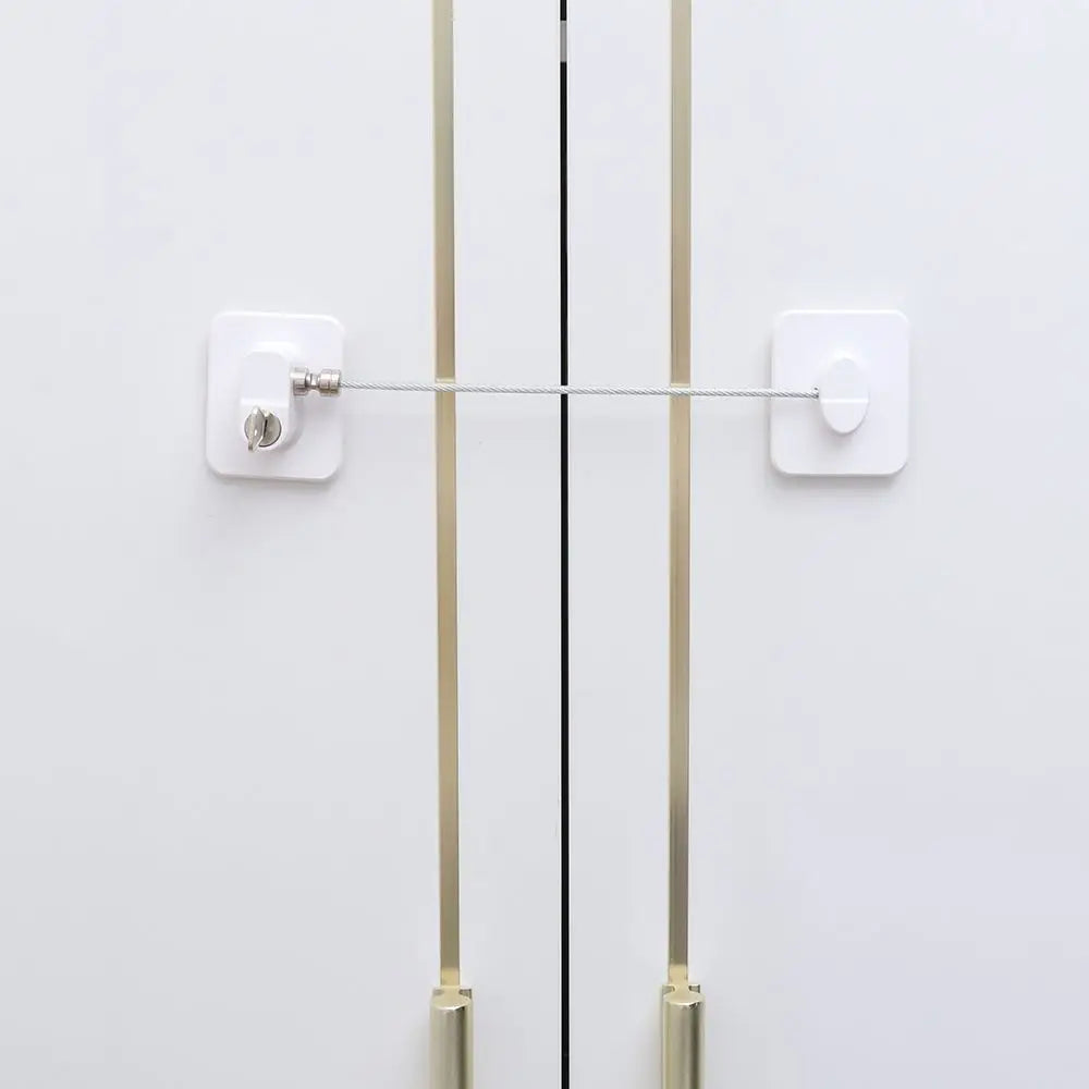 A white child safety cabinet lock mechanism with a long metal bar and mounting plates.