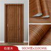 A vertical wooden door featuring a rich brown wood grain finish, shown alongside rolls of the self-adhesive wallpaper materia