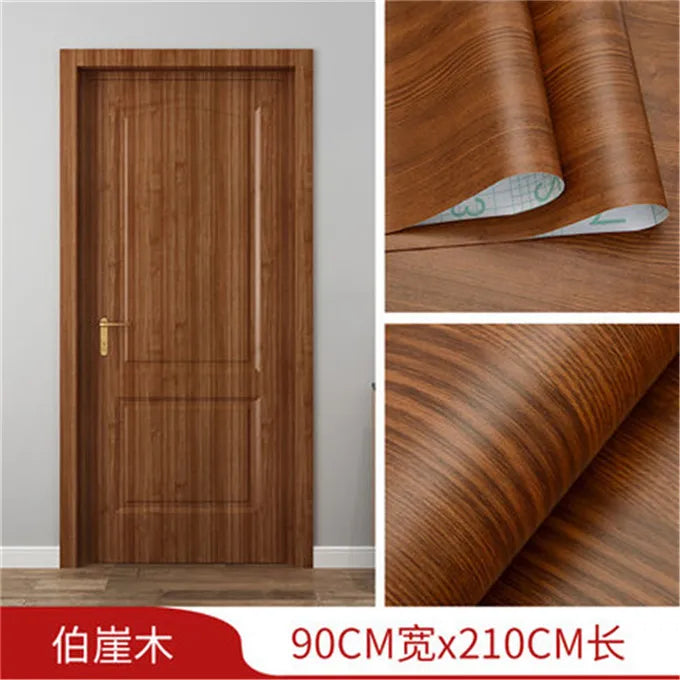 A vertical wooden door featuring a rich brown wood grain finish, shown alongside rolls of the self-adhesive wallpaper materia