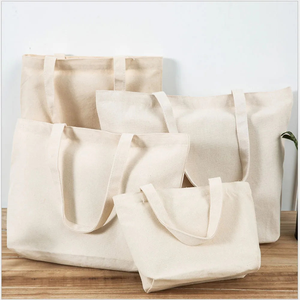 A row of beige canvas tote bags hanging against a white wall on a wooden surface.