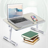 An adjustable foldable laptop desk setup featuring a silver laptop, a smartphone, and a stack of books.