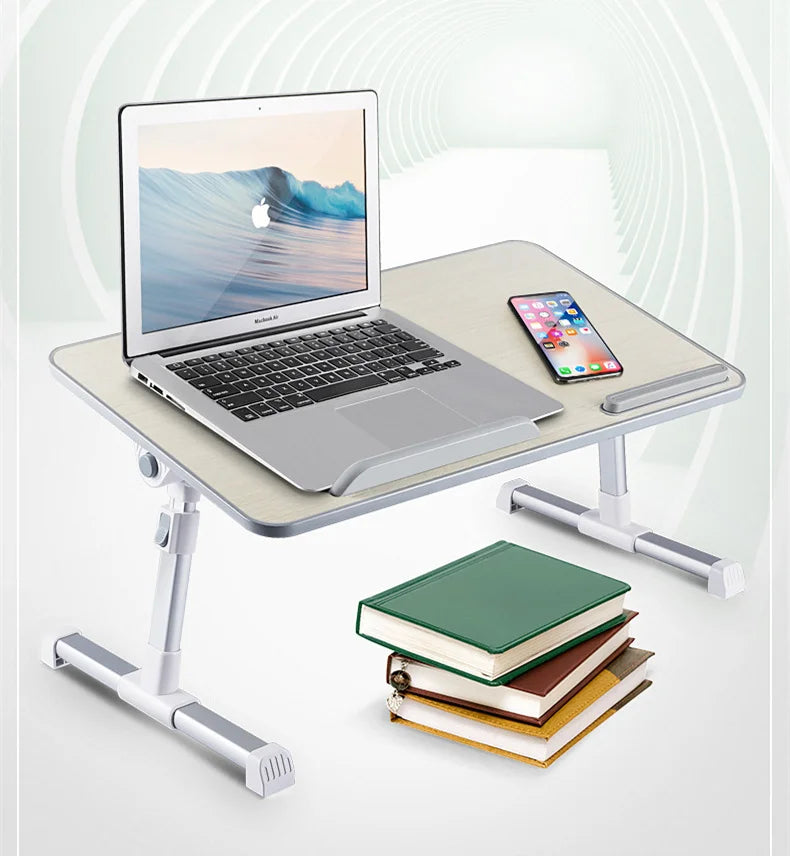 An adjustable foldable laptop desk setup featuring a silver laptop, a smartphone, and a stack of books.