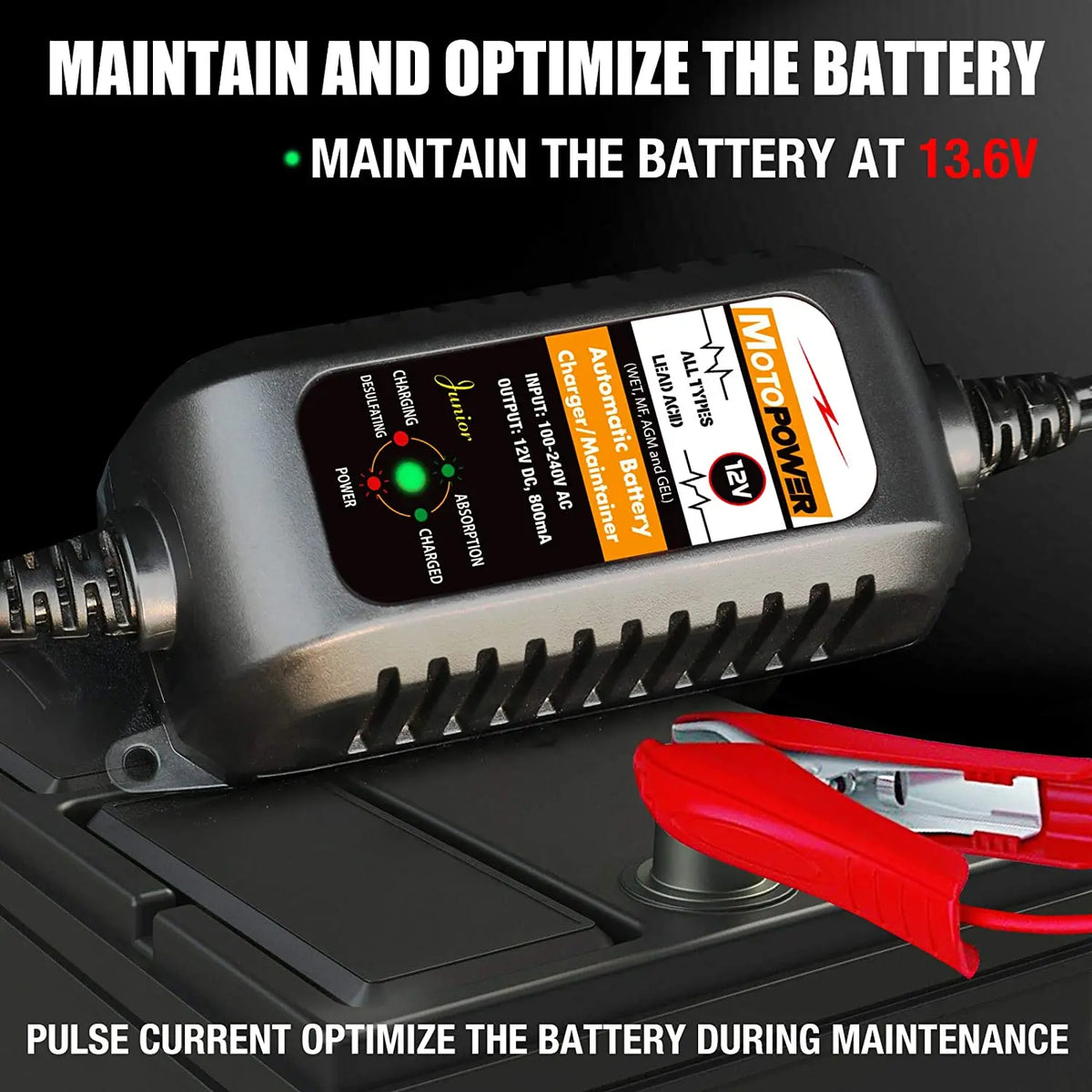A black motorcycle battery charger device with a red clamp is shown on a dark surface.