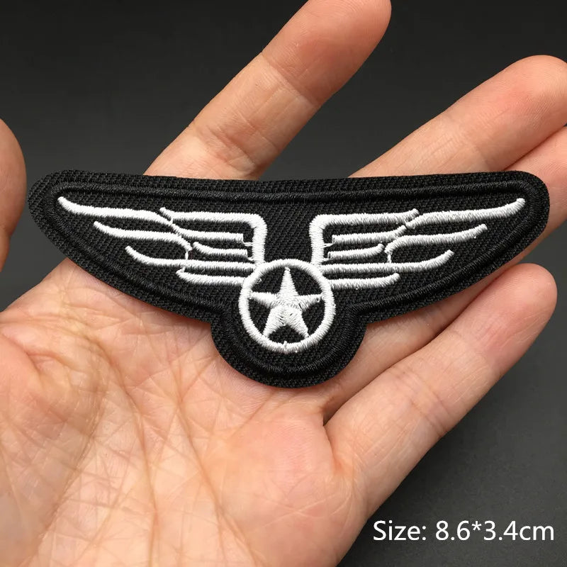 Black embroidered punk skull patches with white wings and star design shown in a hand.