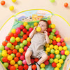 A toddler is playing with a variety of colorful marine balls in an ocean-themed soft play pit.