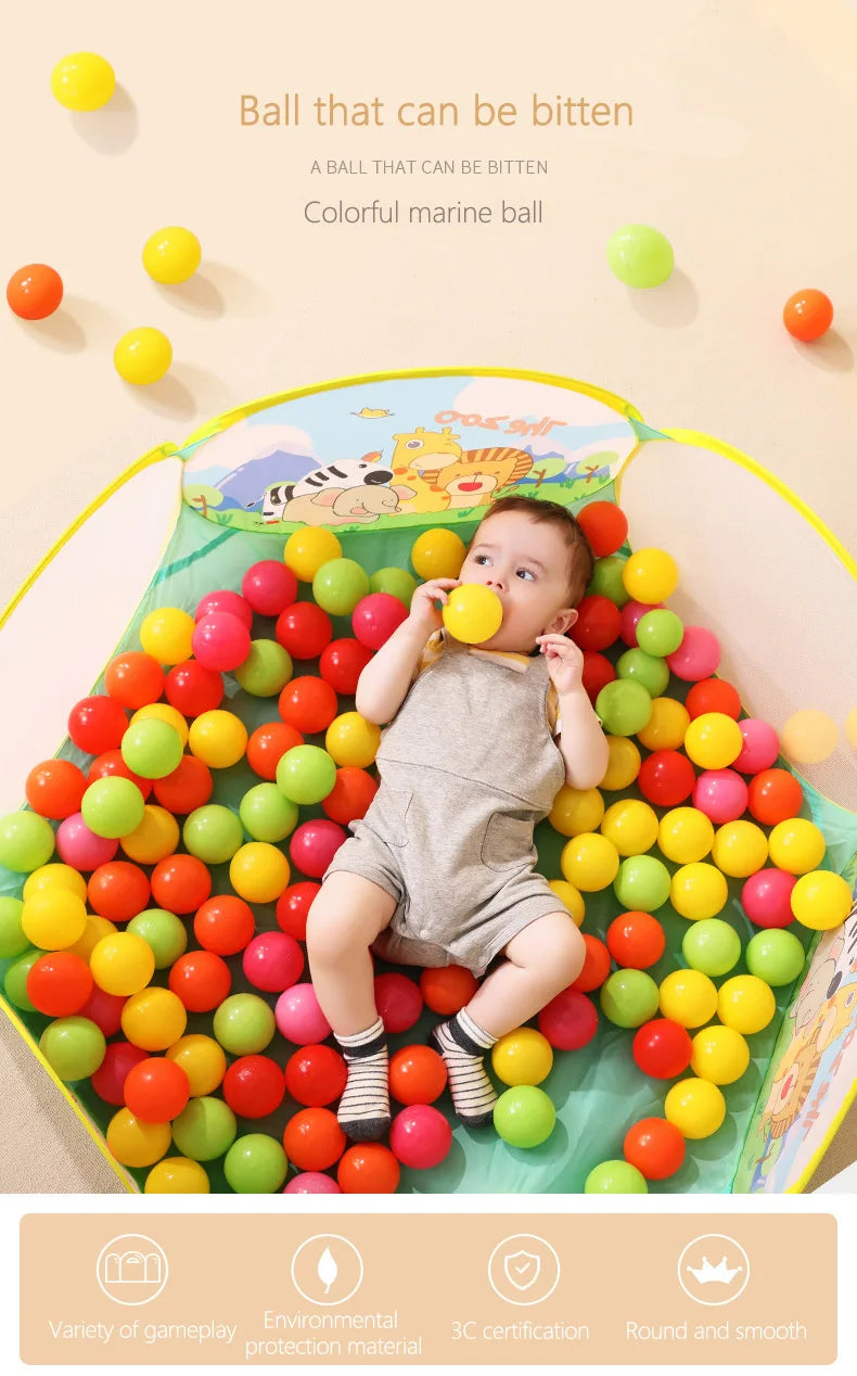 A toddler is playing with a variety of colorful marine balls in an ocean-themed soft play pit.